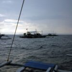 Drei Tauchbancas vor Anker an Monad Shoal unter grauem Morgenhimmel, vom Deck eines anderen Boots aus gesehen