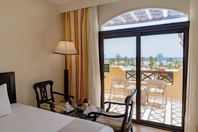 Ein Zimmer mit zwei Sesseln aus dunklem Holz und einem Balkon zum Pool und zum Meer