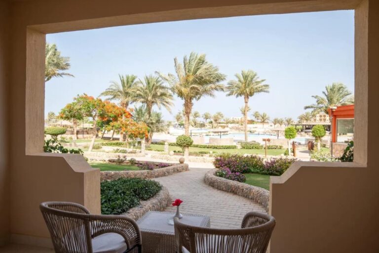 Eine Terrasse mit zwei Korbsesseln vor den blühenden Gärten und Palmen des Blend Elphistone Resorts
