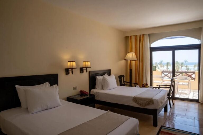 Ein Zweibettzimmer mit Balkon und Blick auf Palmen und Meer