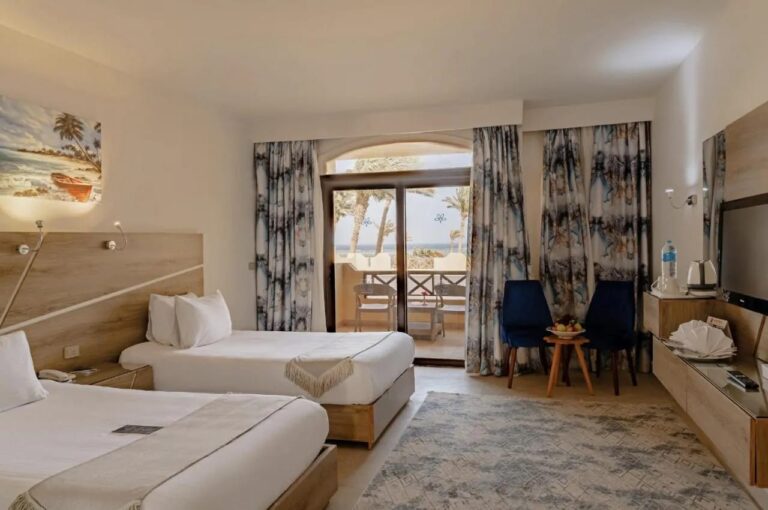 Ein Zweibettzimmer mit zwei blauen Sesseln und einer Glastür zum Balkon