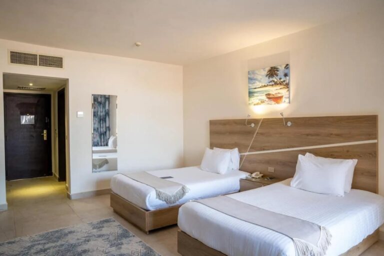 Ein Zweibettzimmer mit Kopfteil aus hellem Holz und einem Strandbild