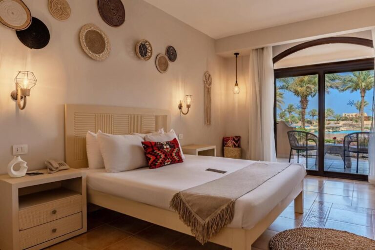 Ein Zimmer mit Doppelbett und geflochtenen Körben als Deko, offen zu einer Terrasse und zum Pool