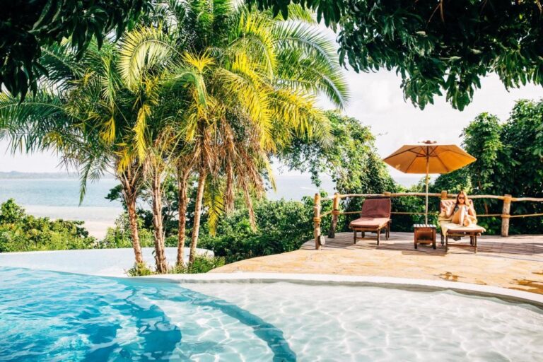 Der Infinity-Pool mit Liegen und orangefarbenem Sonnenschirm, mit Blick aufs Meer