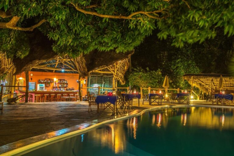 Die Bar und die Tische mit blauen Tischdecken am Pool, bei Nacht