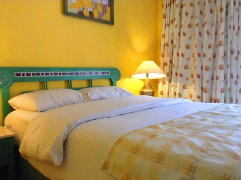 Ein Bett mit grünem, mit Mosaik verziertem Kopfteil vor einer gelben Wand