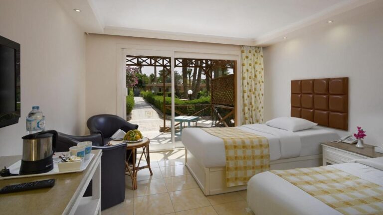 Ein Zweibettzimmer mit zwei schwarzen Sesseln, offen zu einer Terrasse und zum Garten