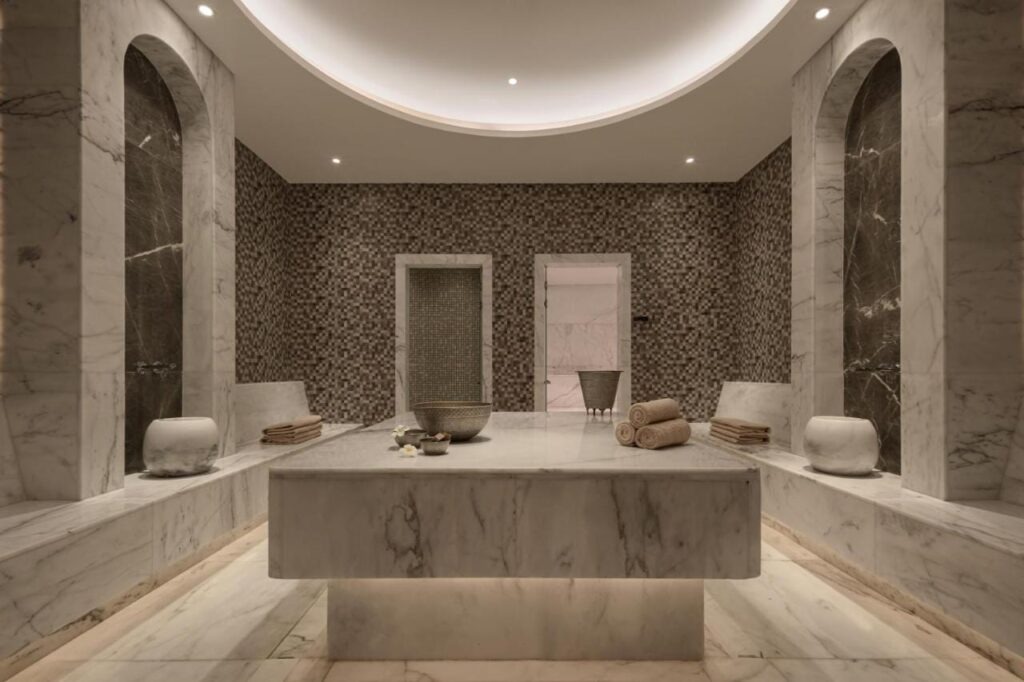 Ein mit Marmor verkleideter Raum im Spa des JAZ Elite Riviera, mit einem großen Steintisch in der Mitte