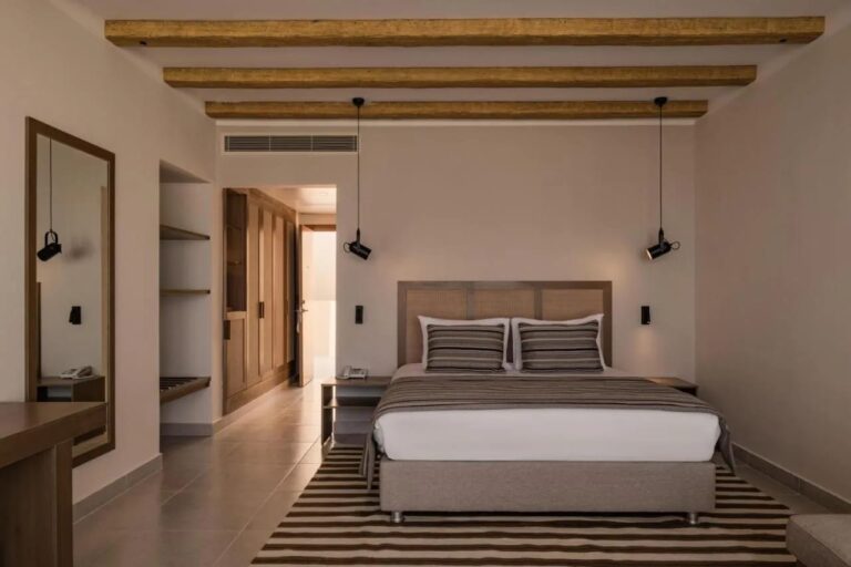 Ein Zimmer mit Doppelbett unter einer Decke mit sichtbaren Holzbalken