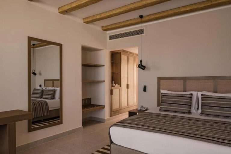 Ein Zimmer mit Doppelbett, großem Spiegel und offenem Ankleidebereich