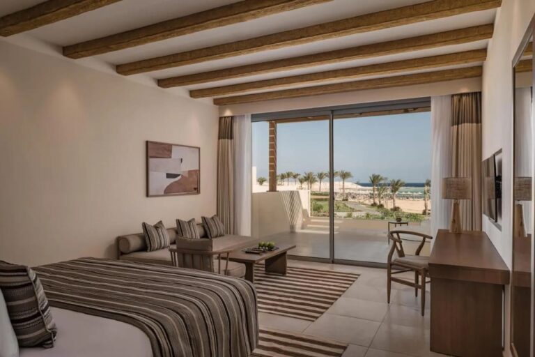 Ein Zimmer mit Sitzecke und einer Fensterfront zum Meer