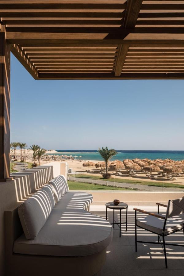 Eine schattige Terrasse mit Sesseln, mit Blick auf den Strand und das Meer