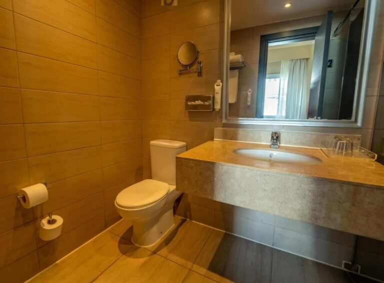 Ein gefliestes Bad mit Toilette, Waschbecken und großem Spiegel