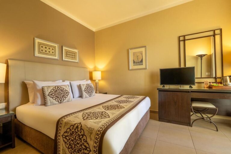 Ein Zimmer mit Doppelbett, Schreibtisch, Fernseher und großem Spiegel