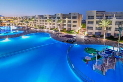 Die beleuchteten Pools des JAZ Soma Beach bei Einbruch der Dunkelheit, zwischen den Gebäuden und Palmen