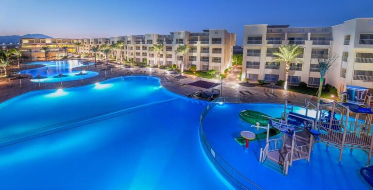 Die beleuchteten Pools des JAZ Soma Beach bei Einbruch der Dunkelheit, zwischen den Gebäuden und Palmen