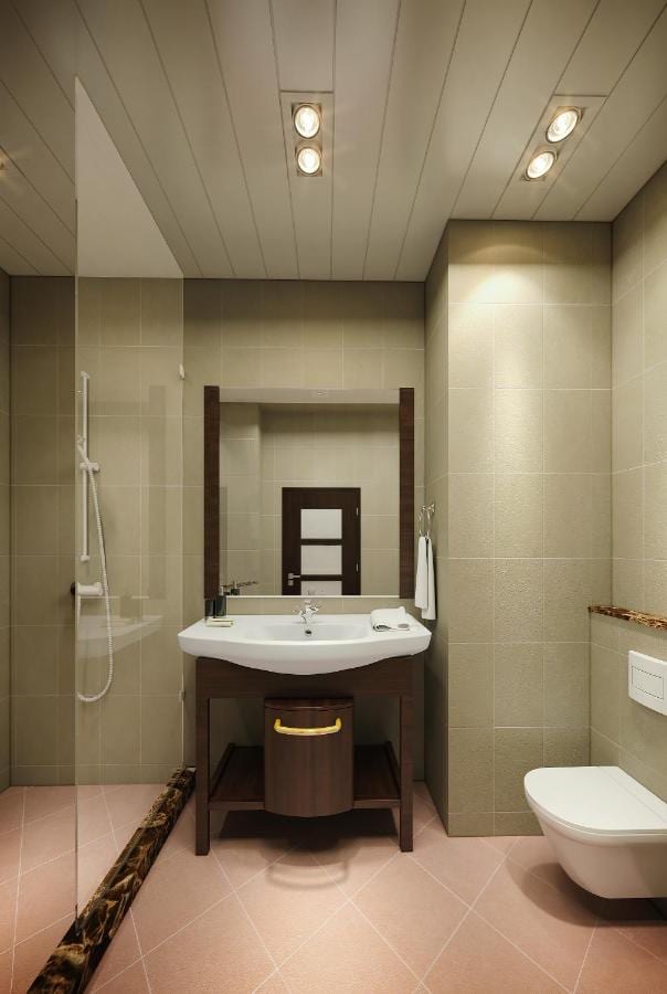 Ein Bad mit verglaster Dusche, Waschbecken auf einem Holzmöbel und Toilette