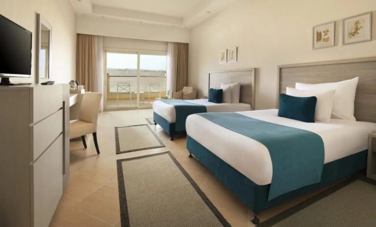 Ein Zweibettzimmer mit Schreibtisch und Balkon