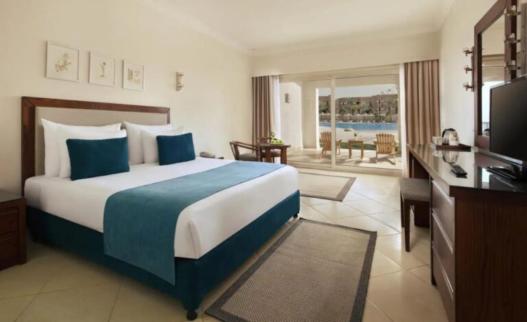 Ein Zimmer mit Doppelbett und Möbeln aus dunklem Holz, mit einer Terrasse zum Pool