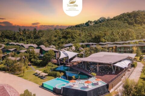 Das Kalima Resort Khao Lak bei Sonnenuntergang aus der Luft, mit seinen Pools und geschwungenen Dächern am Fuß eines bewaldeten Hügels