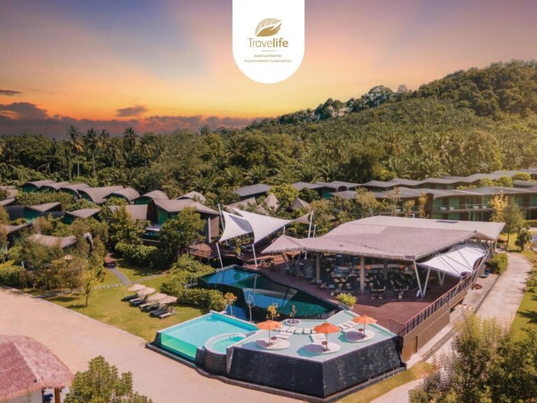 Das Kalima Resort Khao Lak bei Sonnenuntergang aus der Luft, mit seinen Pools und geschwungenen Dächern am Fuß eines bewaldeten Hügels
