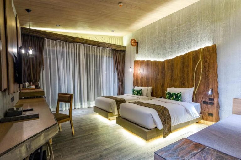 Ein Zweibettzimmer mit von unten beleuchteten Betten, Schreibtisch und Gardinen