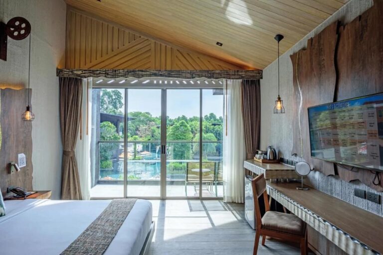 Ein Zimmer unter einer Holzdecke, offen zu einem Balkon mit Blick auf den Pool