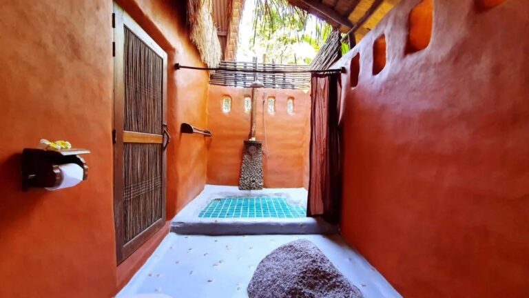 Die halboffene Dusche eines Cottages, mit Vorhang und türkisem Mosaikboden