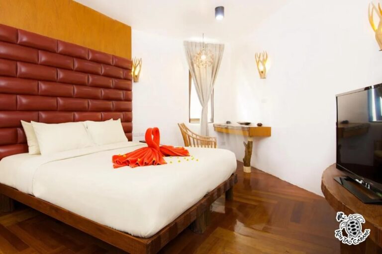 Ein weißes Zimmer im Koh Tao Cabana, mit Doppelbett, gepolstertem rotem Kopfteil und Fernseher