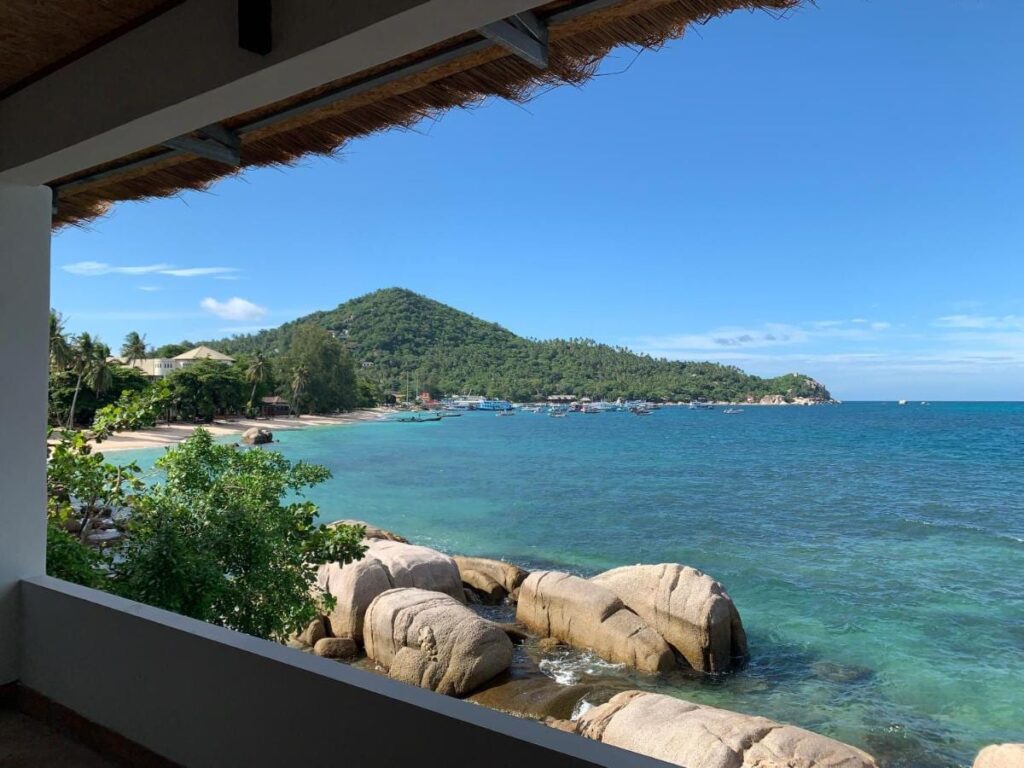 Die Bucht mit ihren Felsen und ankernden Booten, von einer überdachten Terrasse des Koh Tao Heritage aus gesehen