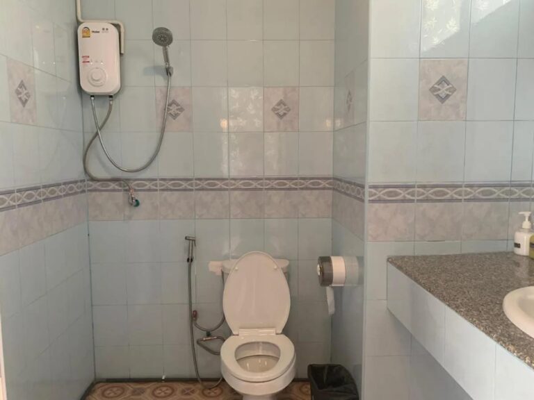 Ein gefliestes Bad mit Dusche und Durchlauferhitzer, Toilette und Waschbecken