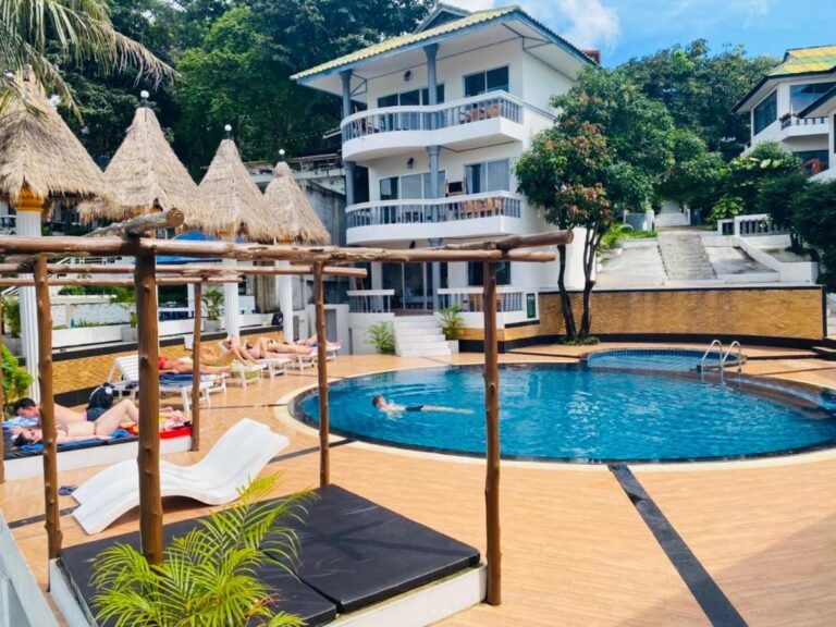 Der Pool des Koh Tao Heritage mit Liegen und Strohschirmen, vor einem Gebäude mit Balkonen
