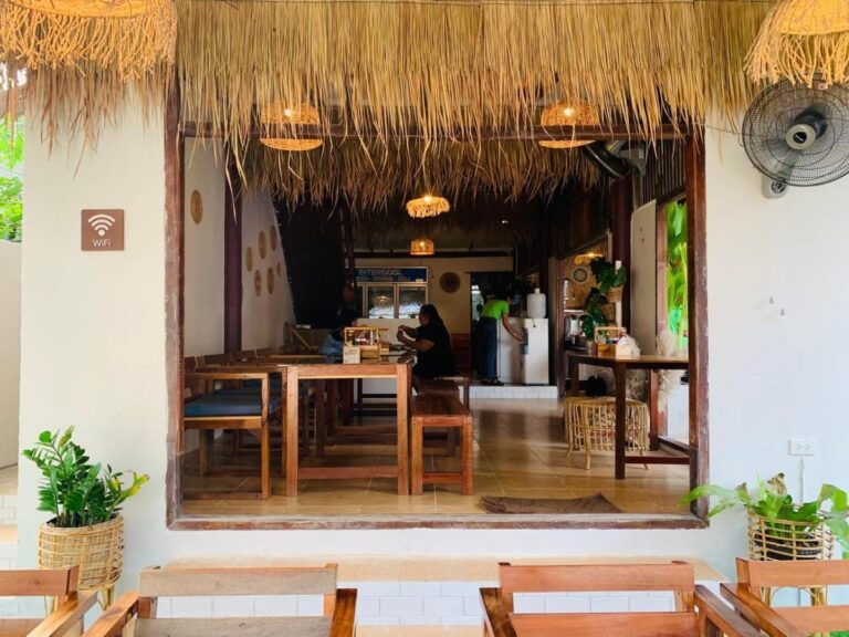 Der Speisesaal des Restaurants mit Holztischen und Hängelampen aus Rattan