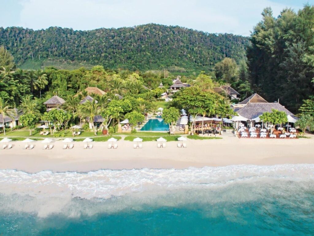 Das Layana Resort vom Meer aus, mit Strand, weißen Sonnenschirmen, Pool und Dächern unter Palmen