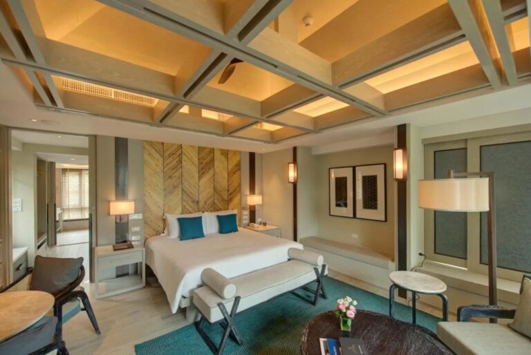 Ein Zimmer mit Doppelbett, Stehlampe und einer Sitzbank unter dem Fenster