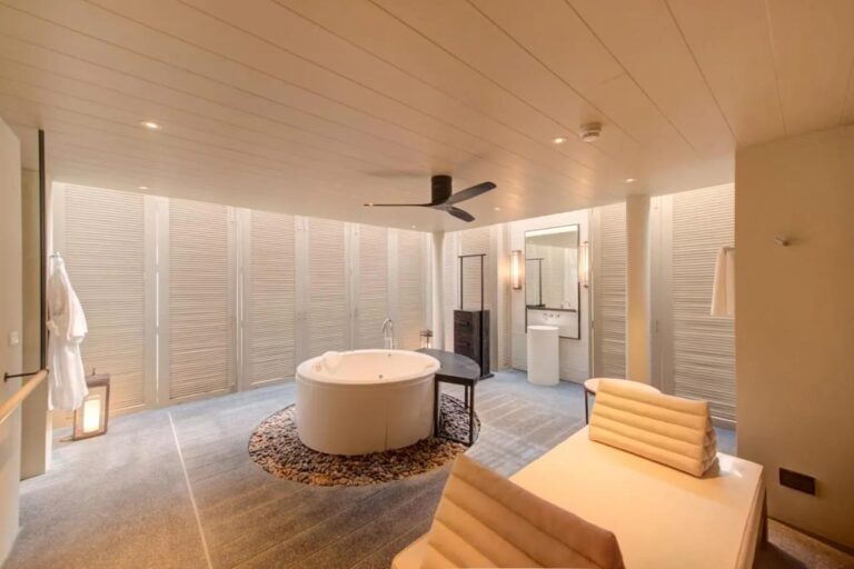 Ein Bad im Layana Resort mit runder Badewanne auf Kieselsteinen und einem aufgehängten Bademantel