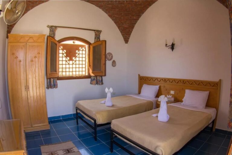 Ein Zweibettzimmer unter einem Ziegelgewölbe, mit Schrank und hölzernen Fensterläden
