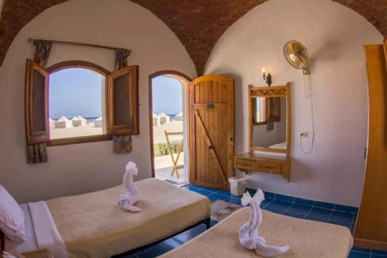 Ein Zweibettzimmer, offen zum Strand, mit weißen Zelten und dem Meer im Hintergrund