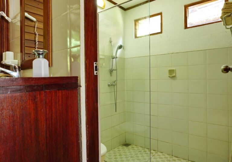 Ein Bad mit Holzmöbel und einer Dusche hinter einer Glaswand