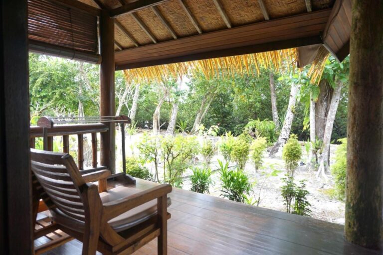 Eine Holzveranda mit Sessel, mit Blick auf einen Garten mit Bäumen