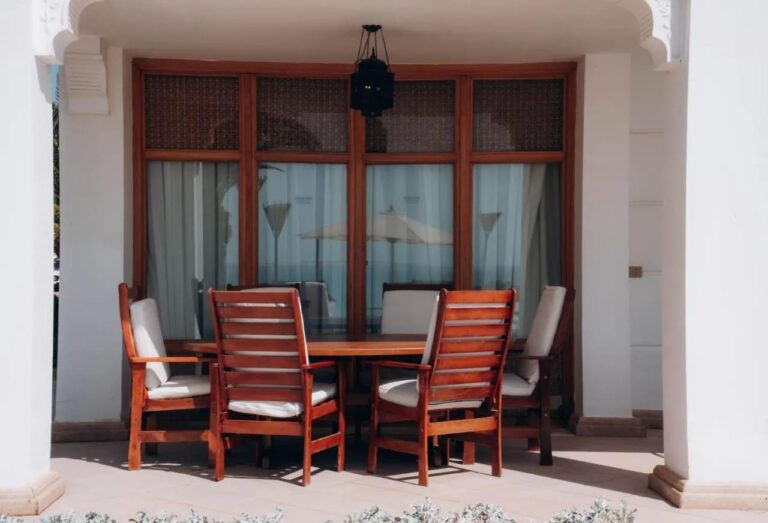 Eine überdachte Terrasse mit Holztisch und sechs Stühlen unter einer Laterne