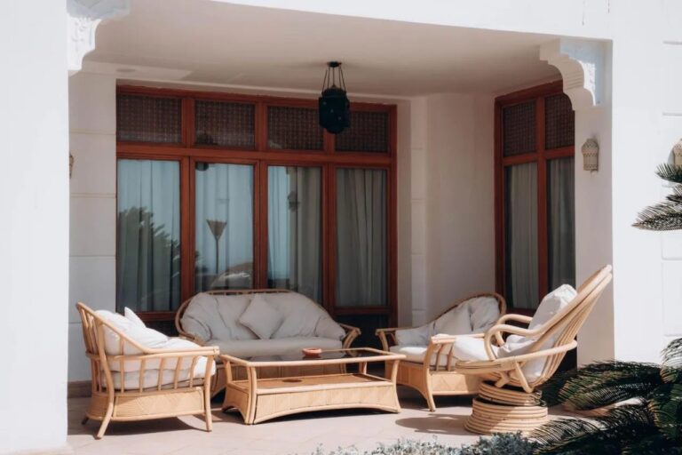 Eine überdachte Terrasse mit Sofa und Sesseln aus Rattan
