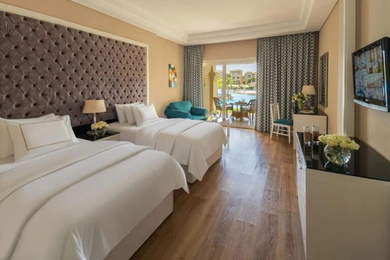 Ein Zimmer mit zwei Doppelbetten und Parkett, offen zum Pool