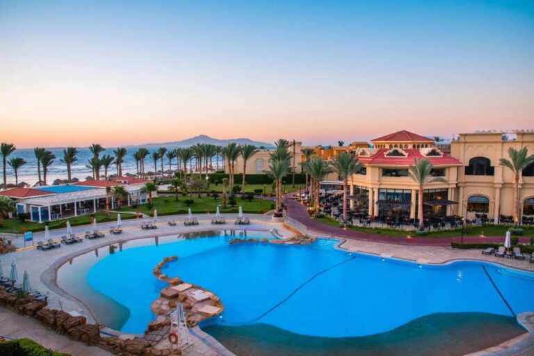 Der große Pool des Rixos Sharm El Sheikh bei Sonnenuntergang, vor Palmen und den Bergen des Sinai
