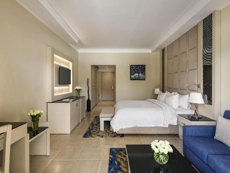 Ein Zimmer mit Doppelbett, blauem Sofa und weißen Blumen auf dem Tisch
