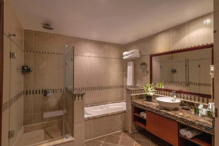 Ein Bad mit Glasdusche, Badewanne und großem Spiegel