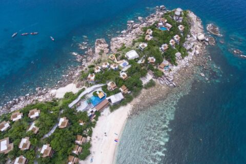 Luftaufnahme des Sai Daeng Resorts mit seinen Bungalows auf einer Felsspitze, den Pools und dem Sandstrand