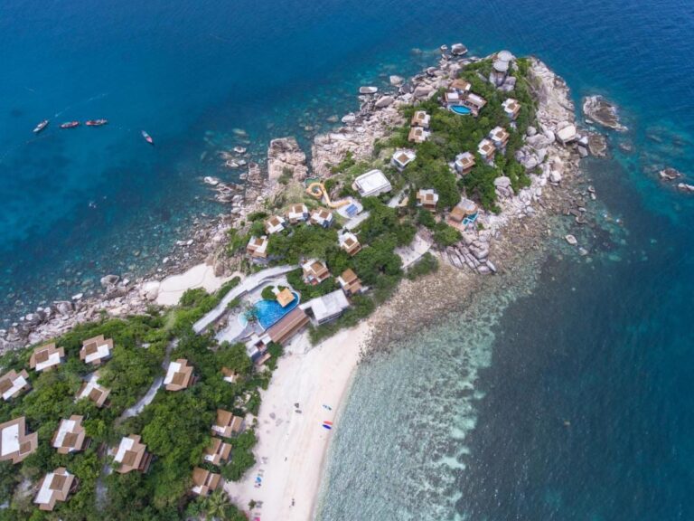 Luftaufnahme des Sai Daeng Resorts mit seinen Bungalows auf einer Felsspitze, den Pools und dem Sandstrand
