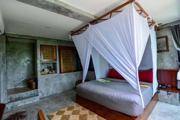 Ein Zimmer mit Bett unter Moskitonetz und einer Tee-Ecke in einer Wandnische
