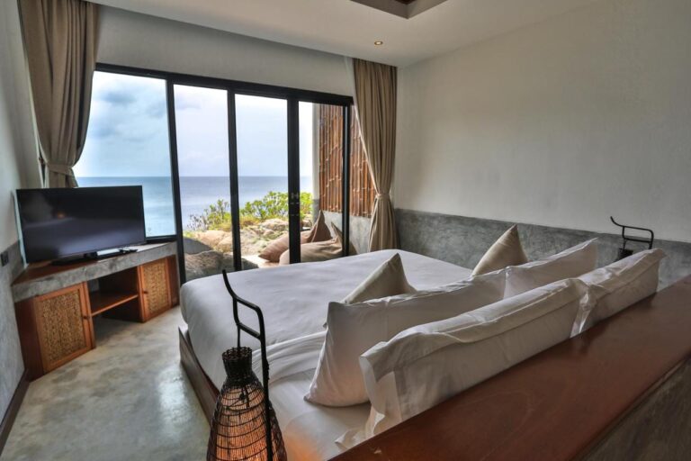 Ein Zimmer des Sai Daeng Resorts mit Glasfront zum Meer und zu den Felsen